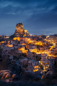 Illuminated buildings in city against sky at dusk