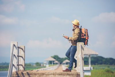 Man holding hat standing against sky
