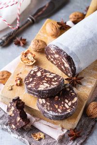 Traditional italian dessert - christmas chocolate salami with broken biscuits and walnuts on a table