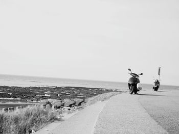 Rear view of man walking on beach against clear sky