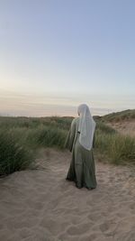 Rear view of woman standing at desert against clear sky