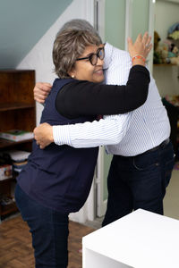 Older man hugging older woman, talking and celebrating birthday indoors