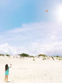 Rear view of girl flying kite at beach