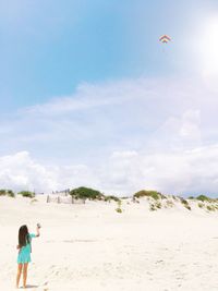 Rear view of boy standing on beach against sky