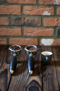 High angle view of coffee in containers on table against brick wall at cafe
