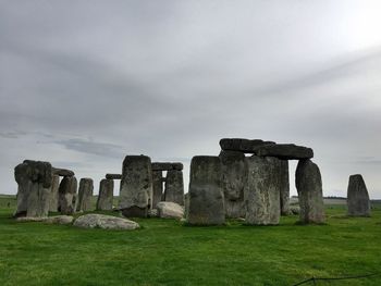 Old ruins on field against cloudy sky