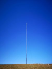 Low angle view of wind turbines on field against clear blue sky