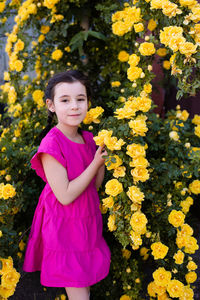 Portrait of young woman standing amidst yellow flowering plants
