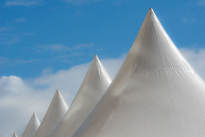 Festival tent with pointed roofs rising against a blue sky with white clouds