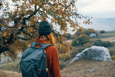 Rear view of woman standing by tree