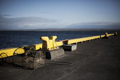 Close-up of yellow container on table by sea against sky