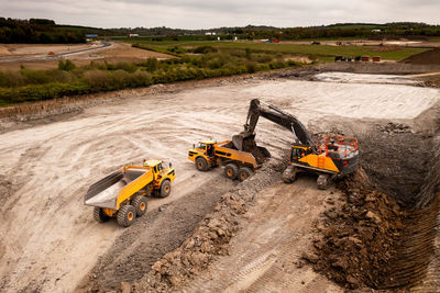 Aerial view a mechanical digger  loading a dumper truck in construction industry on brownfield