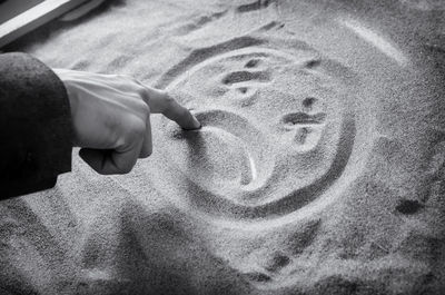 Cropped hand drawing on sand at beach