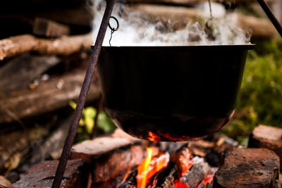 Close-up of a black pot of hot, steaming soup outdoors. hiking and campfire cooking with bright 