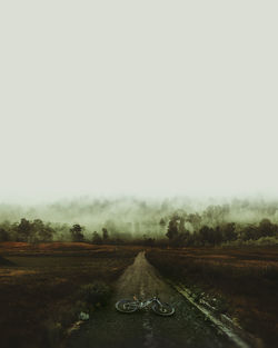 Road amidst trees on field against clear sky