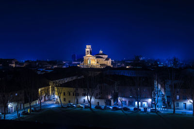 Illuminated buildings against blue sky at night