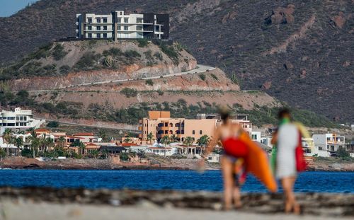 Full length of people on beach against buildings