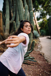 Latina girl with boho shirt dancing surrounded by cactus'