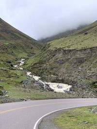 Scenic view of road by mountains against sky