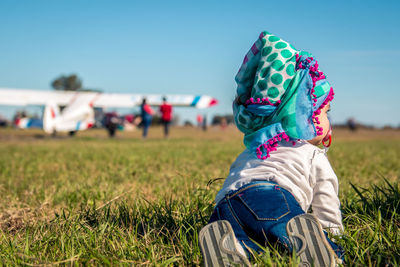 Rear view of girl crawling on grass against sky