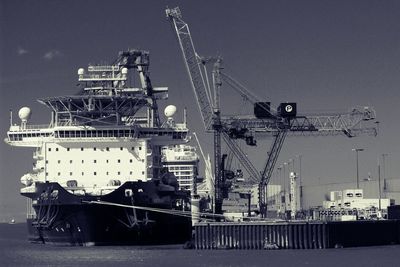 Crane by ship at sea against clear sky