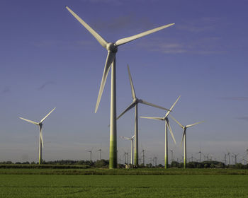 Windmills on field against sky