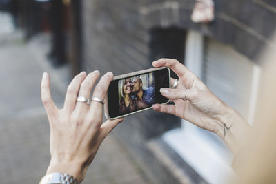Man kissing woman as she takes selfie through smart phone