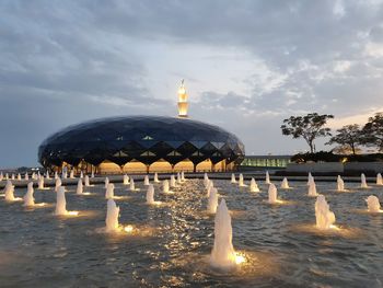 Gazebo by illuminated building against sky