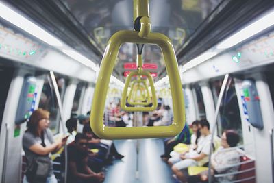 Close-up of handle in train with people in background