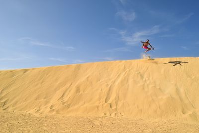 Man jumping in desert against sky