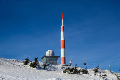 Built structure on snow covered land against blue sky