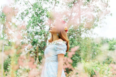 Thoughtful woman standing against trees