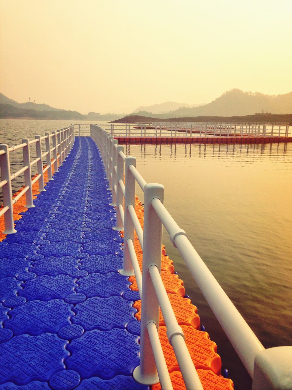 water, railing, the way forward, tranquility, clear sky, scenics, tranquil scene, diminishing perspective, nature, sea, beauty in nature, pier, transportation, bridge - man made structure, mountain, built structure, river, sky, outdoors, vanishing point