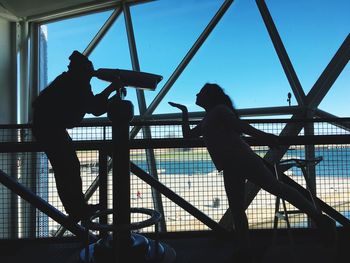 Silhouette boy on railing against sky