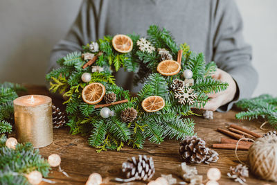 A male florist makes a new year's wreath with fresh fir branches, pine cones and dried fruits. 