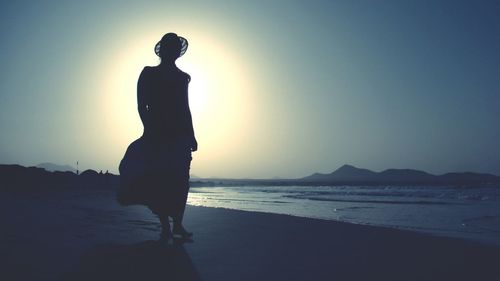 Silhouette woman at beach against sky