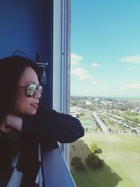 Young woman looking away in city against sky