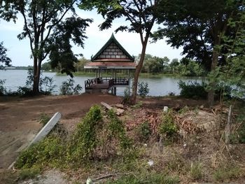 Gazebo by lake in forest against sky