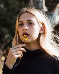 Portrait of young woman holding sunglasses