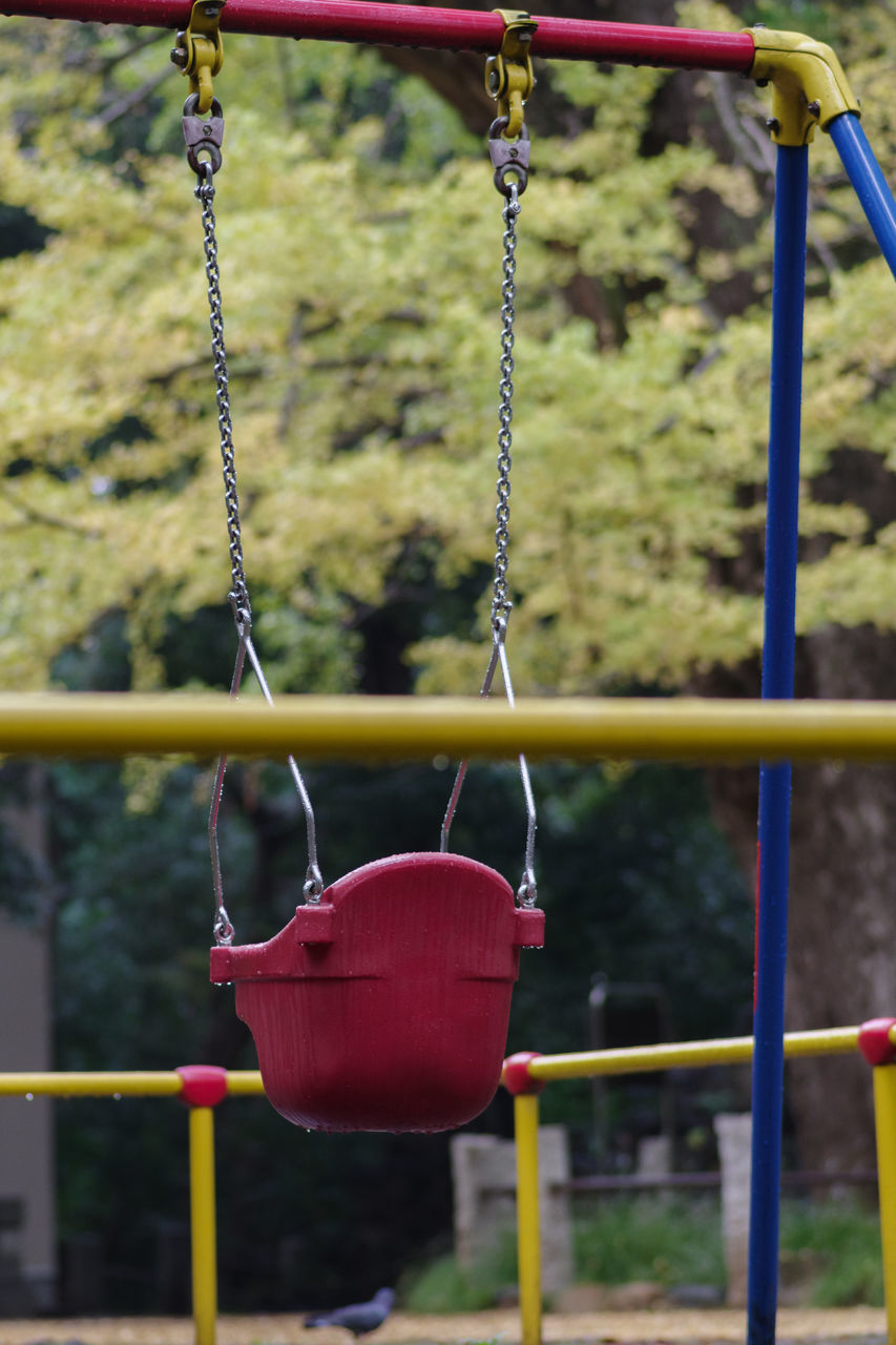 CLOSE-UP OF RED SWING HANGING ON PLAYGROUND