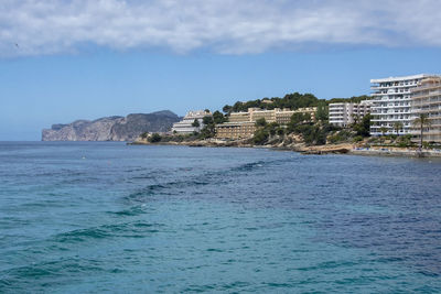 Scenic view of sea by buildings against sky