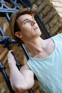 Low angle view of thoughtful young man standing against gate