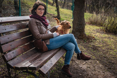 Man with dog sitting on bench in park