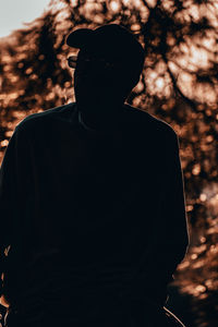 Portrait of man standing against silhouette tree