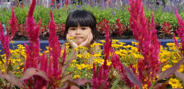 Portrait of girl with flowers against plants