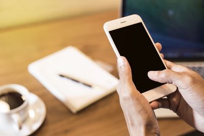 Midsection of man using smart phone on table