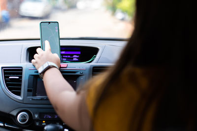 Midsection of man using mobile phone in car