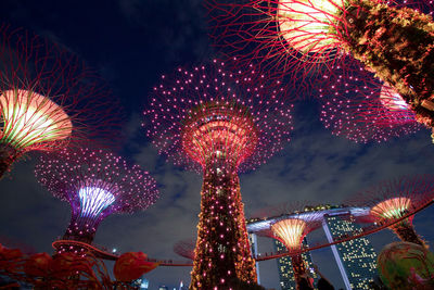 Low angle view of illuminated supertrees against sky at night