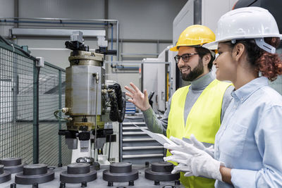 Happy engineer holding blueprint with colleague in office