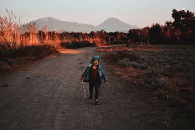 Full length of boy walking on dirt road